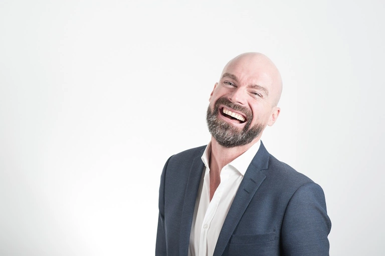 annoying bald man in a business casual suit laughs