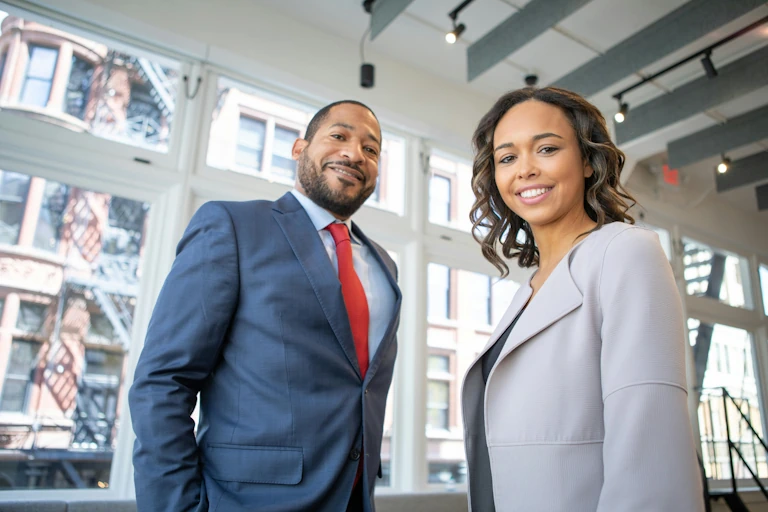 Man and woman in suits looking down in the camera