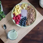 healthy meal with berries, yoghurt, fruits, ananas and oats on a wooden board