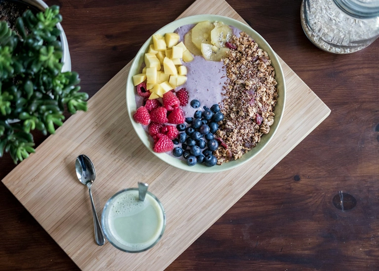 healthy meal with berries, yoghurt, fruits, ananas and oats on a wooden board