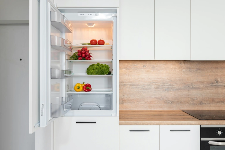 Fridge half empty with vegetables inside