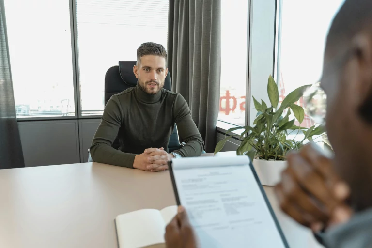 Man sitting on a chair facing another person who looks at a document