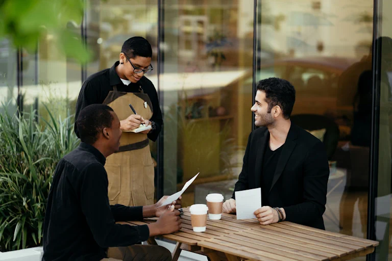 Waiter taking the order of two men sitting at a table
