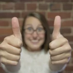 Woman smiling and giving two thumbs up