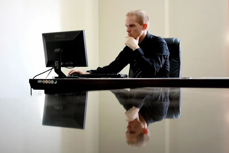 businessman sitting and using a computer with a stern look