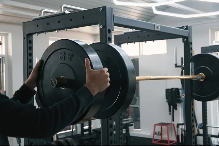 Man Adjusting Barbell Weights in Gym