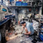 Man crouching working with a metal tool