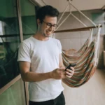 Man Smiling While Holding Phone in Hands